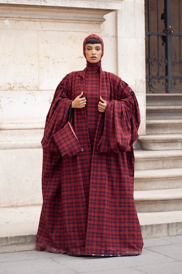 Una invitada luce un espectacular vestido largo a cuadros rojos y negros con mangas voluminosas, un tocado a cuadros a juego y un clutch oversize a cuadros a juego en el exterior del desfile de Louis Vuitton durante la Semana de la Moda de París, el 30 de septiembre de 2025.
