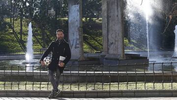 Eduardo Verdú, autor de 'Todo lo que ganamos cuando perdimos todo', sobre el futbolista de la RDA Lutz Eigendorf, posa ante un trozo del muro conservado en el parque de Berlín en Madrid.