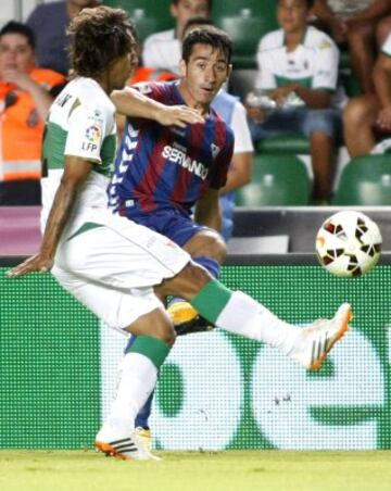 El delantero del Eibar Saúl Berjón (d) centra el balón ante la presión del uruguayo Damián Suárez (i), del Elche, durante el encuentro de la cuarta jornada de Liga de Primera División que se juega esta noche en el estadio Martínez Valero, en Elche.