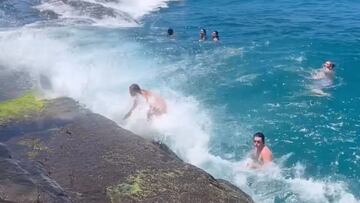 Bañistas empujados contra las rocas por una ola en China Wall, Oahu, Hawái