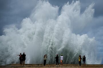 La gente toma fotografías de las olas que se estrellan contra el Malecón, provocado por el paso del huracán Milton en el Golfo de México, en La Habana, Cuba.