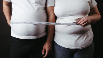 Overweight couple standing together wrapped with measure tape. Dieting, family weight loss and health care