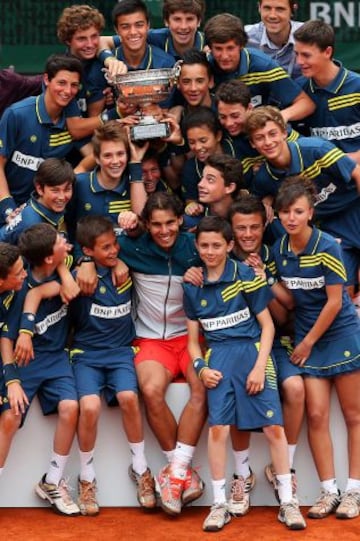 Rafa Nadal rodeado de los recogepelotas del torneo y el trofeo de Roland Garros 2013 después de derrotar a su compatriota David Ferrer en la final