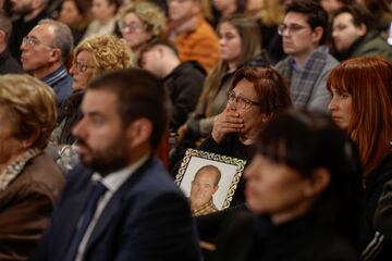 Una mujer llora durante la misa funeral sosteniendo un cuadro de un ser querido, fallecido durante als inundaciones.