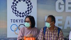 Una pareja de habitantes de Bangkok, con m&aacute;scaras delante de un cartel promocional de Tokio 2020. 