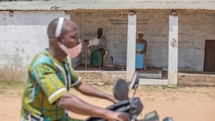 A man drives a motorcycle past a voodoo temple in Ouidah, Benin.