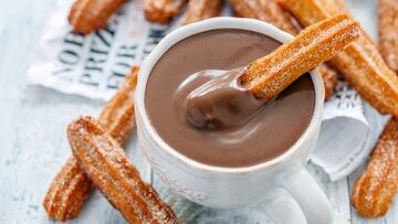 Churros with a cup of hot chocolate closeup, selective focus.