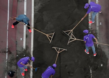 Los oficiales de pista alisan la arena en el foso de aterrizaje antes de la final de salto de longitud masculino. 