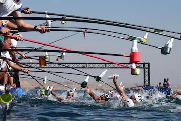 Varios nadadores recogen botellas de agua, mediante un curioso sistema, a su paso por un punto de avituallamiento durante la Copa del Mundo de nataci車n en aguas abiertas en Neom, Arabia Saud赤. La imagen fue tomada en la prueba de 10 kil車metros masculinos de los NEOM Beach Games, que incluyen diversos deportes acu芍ticos y de aventura.