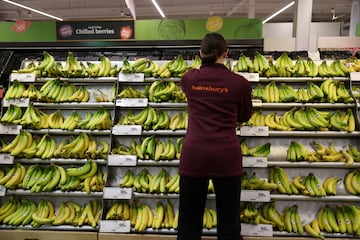 An employee arranges Fairtrade bananas inside a Sainsbury's supermarket in Richmond, West London, UK.