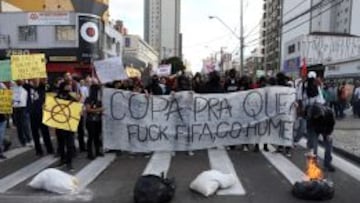 CURITIBA. Un grupo de manifestantes encapuchados portan una pancarta en contra del Mundial y de la FIFA y se disponen a cortar y a prender fuego en una calle de Curitiba.