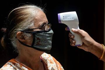 A health worker checks the body temperature of a woman at a containment zone implemented as a preventive measure against the COVID-19 coronavirus in Chennai.