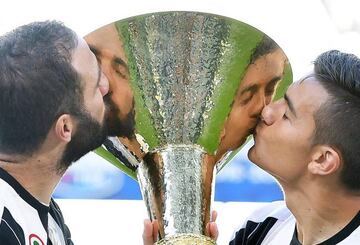 Juventus' Gonzalo Higuaín and Paulo Dybala give the Serie A trophy a kiss.