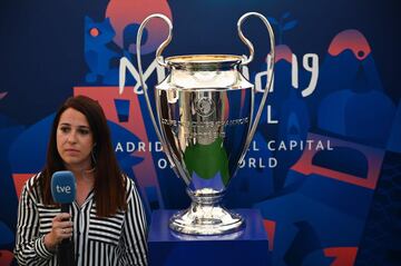 A TV reporter stands next to the UEFA Champions League trophy after it was unveiled in Madrid on May 29, 2019 ahead of the final football match between Liverpool and Tottenham Hotspur on June 1. 