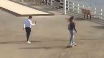 Influencer en longboard por un paseo marítimo mientras la graban.