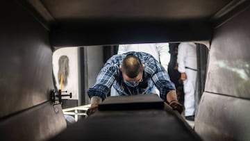 (FILES) In this file photo taken on June 1, 2020 Mauricio Navarrete, 27, unloads a coffin with a victim of COVID-19 from a hearse at a cemetery Mexico City. - Almost six months after it was first detected in Latin America, the coronavirus death toll has r