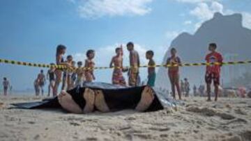 Niños observan los cuerpos de las dos víctimas del derrumbe del carril bici de Río de Janeiro, en la playa de São Conrado.