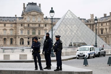 Agentes de policía se encuentran cerca de la pirámide del museo del Louvre.