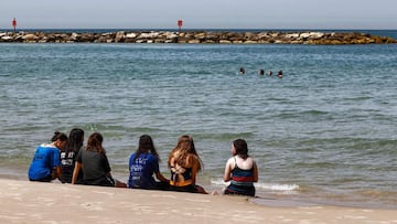 People sit along the shore at a beach in Israel's Mediterranean coastal city of Tel Aviv on April 7, 2021. (Photo by JACK GUEZ / AFP)