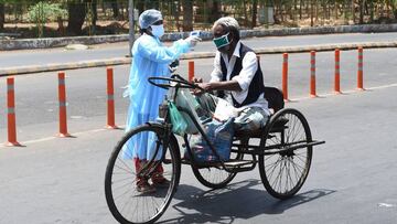 A health worker checks the body temperature of a man with mobility impairment during a government-imposed nationwide lockdown as a preventive measure against the COVID-19 coronavirus in Ahmedabad on April 8, 2020. (Photo by SAM PANTHAKY / AFP)