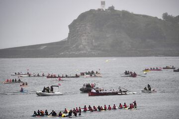 Una flotilla de embarcaciones que incluye barcos y kayaks escoltan la llama olímpica transportada a bordo de una trainera.
