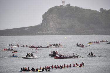 Una flotilla de embarcaciones que incluye barcos y kayaks escoltan la llama olímpica transportada a bordo de una trainera.