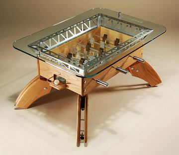Este modelo es una mesa de café y un futbolín. Es un diseño del creativo inglés Howard Bushell. Está realizado en madera de álamo de calidad y cristal. Tiene 20 cm de altura, lo que permite que se pueda jugar sentados en el suelo. Su precio ronda los 3.000 euros.