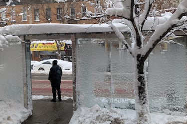 Un hombre espera en una parada de autobús cubierta de nieve en el barrio de Brooklyn.