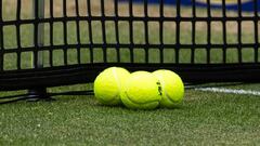 Tres pelotas de tenis en una pista de hierba.
