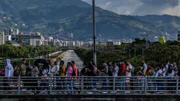 People wait in line as they commute near a metro station on their way home before a curfew, amid the COVID 19 pandemic in Medellin, Colombia on March 31, 2021. - Authorities placed several regions including Antioquia department and its capital Medellin under a new lockdown after an increase in coronavirus cases. (Photo by JOAQUIN SARMIENTO / AFP)