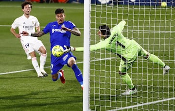 Thibaut Courtois desvía el balón ante la oposición de Mathías Olivera.