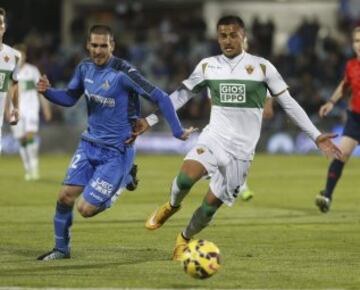 El centrocampista del Getafe Juan Rodríguez (i) lucha un balón con el delantero del Elche Cristian Herrera, durante el partido correspondiente a la undécima jornada de Liga de Primera división que disputan en el estadio Coliseum Alfonso Pérez. 