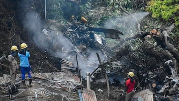 Firemen and rescue workers stand next to the debris of an IAF Mi-17V5 helicopter crash site in Coonoor, Tamil Nadu, on December 8, 2021. - A helicopter carrying India's defence chief General Bipin Rawat crashed, the air force said, with a government minister at the scene saying at least seven people were dead. (Photo by AFP)