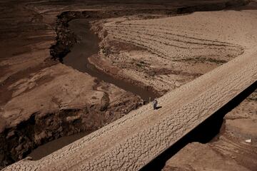 Un hombre camina sobre el suelo agrietado del embalse de Baells, una infraestructura hidráulica española situada en el río Llobregat, en la comarca del Bergadá, provincia de Barcelona. 