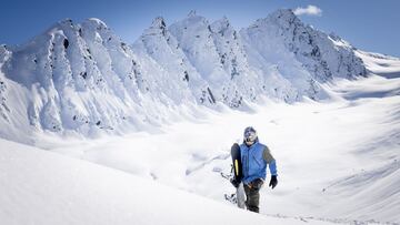 Travis Rice andando con su tabla de snowboard sobre la nieve y las montañas nevadas de Alaska (Estados Unidos).