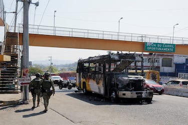 Soldados pasan junto a un autobús incendiado por desconocidos, tras retenes y ataques incendiarios perpetrados por miembros del crimen organizado en varios estados. 