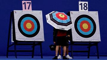 Desde agosto tendrá lugar, en la Explanada de los Inválidos, la competición de tiro con arco en los Juegos Olímpicos de París. En la imagen, un participante aparece durante el entrenamiento entre dos dianas, portando un paraguas con los mismos colores que los blancos donde impactan las flechas. 