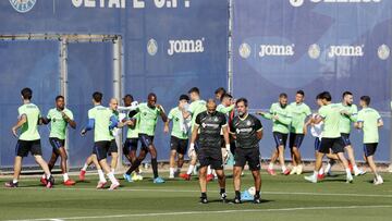 Quique charla con Emilio, preparador de porteros, durante el calentamiento del equipo en un entrenamiento.