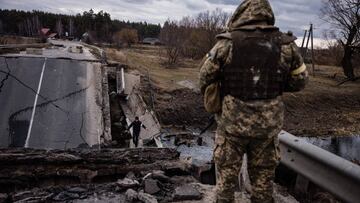 An Ukrainian serviceman looks at a civilian crossing a blown up bridge in a village, east of the town of Brovary on March 6, 2022. - The Russian push on Kyiv is becoming more deadly and indiscriminate despite Moscow&#039;s denials that it is targeting civ