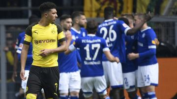 Schalke&#039;s players celebrate a penalty, while Dortmund&#039;s English midfielder Jadon Sancho walks past during the German first division Bundesliga football match Borussia Dortmund v FC Schalke 04 in Dortmund, western Germany on April 27, 2019. (Phot