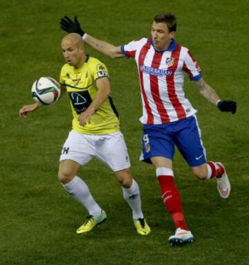 El jugador del L'Hospitalet Valentín (i) con el balón ante el delantero croata del Atlético de Madrid Mario Mandzukic (d) durante el partido de vuelta de los dieciseisavos de final de la Copa del Rey, disputado esta tarde en el estadio Vicente Calderón. 