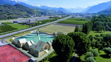 Recreación de la piscina de olas para el surf de Wavegarden en Alaïa Chalet: Sion, Valais, Suiza. Con las montañas de fondo, al lado de unas pistas de tenis.