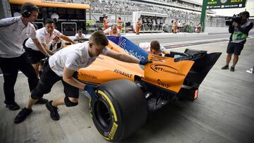 Mechanics push the car of McLaren's Spanish driver Fernando Alonso into the garage during the second practice session of the Formula One Russian Grand Prix at the Sochi Autodrom circuit in Sochi on September 28, 2018. (Photo by Alexander NEMENOV / AFP)