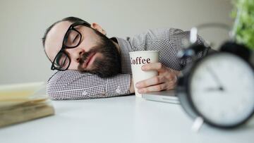 Man sleeps on office table over laptop with coffee