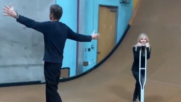 Tony Hawk abre los brazos en se&ntilde;al de milagro mientras una chica aguanta su muleta en la rampa de Vert que tiene en Los &Aacute;ngeles, en marzo del 2022, tras su fractura de f&eacute;mur. 