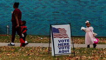 People participating in Halloween festivities walk past a voting sign outside the River Rouge Civic Center in the Wayne County suburb of Detroit, Michigan, U.S., October 31, 2024. REUTERS/Shannon Stapleton TPX IMAGES OF THE DAY