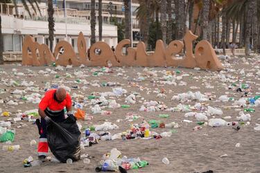 Un operario del servicio de limpieza municipal de Málaga recoge restos de basura en la playa de La Malagueta.