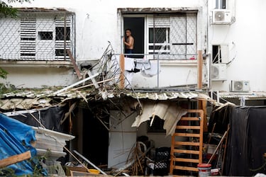 Un hombre israel mira desde una ventana de un edificio que fue alcanzado por los cohetes lanzados desde Gaza hacia Israel en Ashkelon.