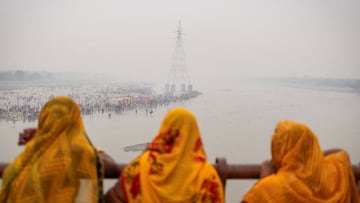 Hindu devotees stand on a bridge as others worship the Sun god on the banks of Yamuna river during the Hindu religious festival of Chhath Puja on a smoggy morning in Noida on the outskirts of New Delhi, India, October 28, 2025. REUTERS/Adnan Abidi