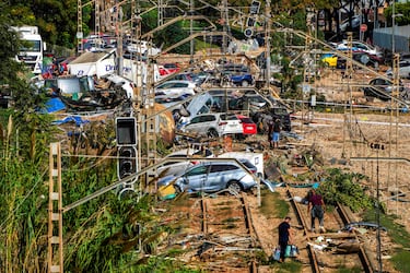 La gente camina entre autos amontonados sobre las vías del tren en Valencia, España.